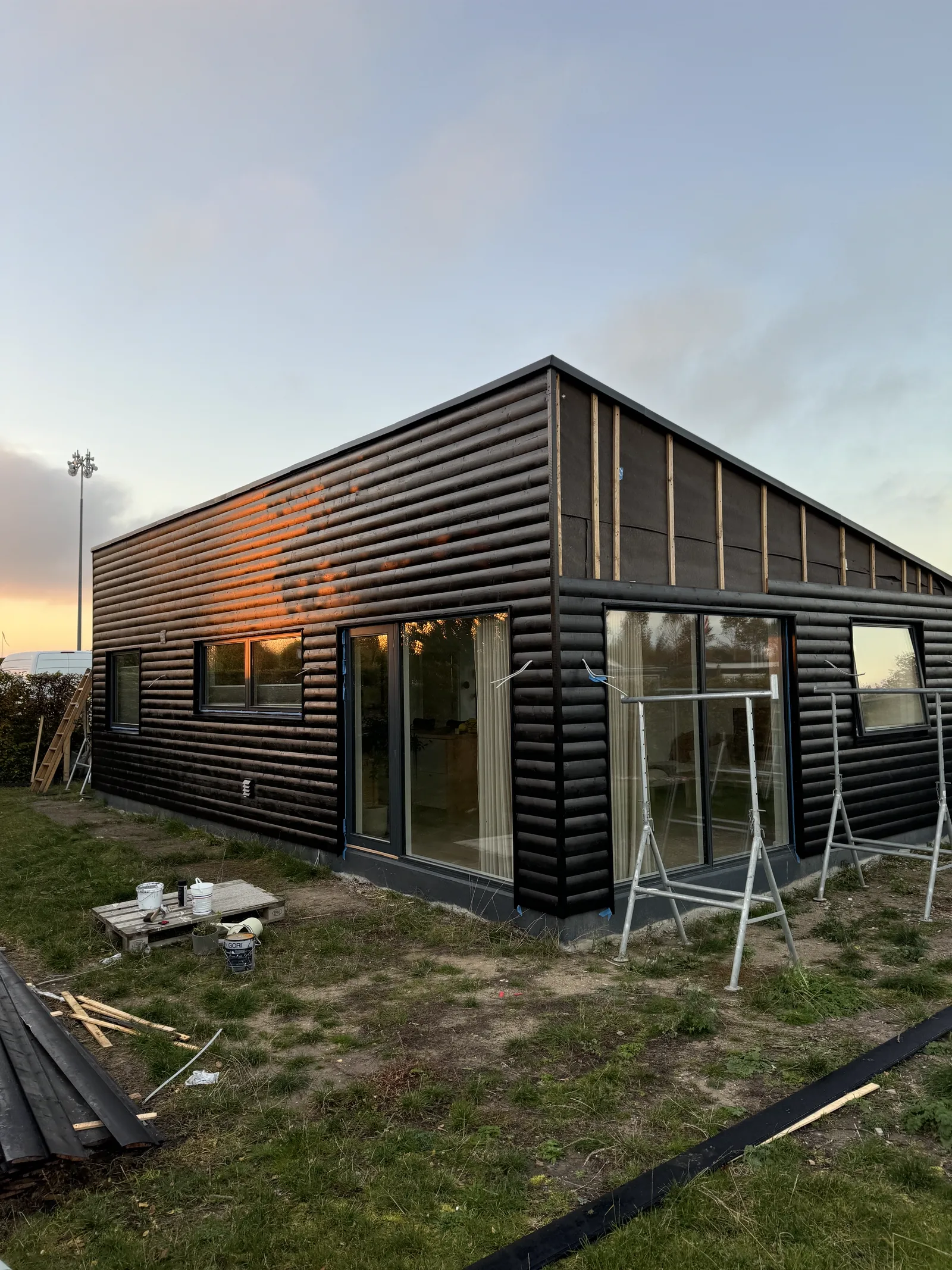 Kolonihavehus: facaden i aftenlys med lys indefra